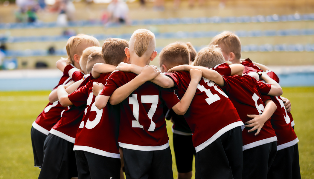 Photo of a group young boys in sports clothers huddled round